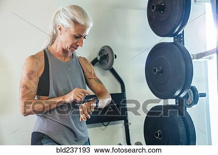 Caucasian woman tapping smart watch in gymnasium View Large Photo Image Stock Image - Caucasian woman tapping smart watch in gymnasium. Fotosearch