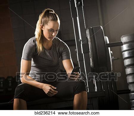 Caucasian woman texting on cell phone in gymnasium View Large Photo Image Picture - Caucasian woman texting on cell phone in gymnasium. Fotosearch