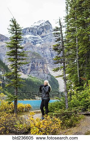 Stock Photography - Caucasian woman using binoculars at mountain lake. Fotosearch