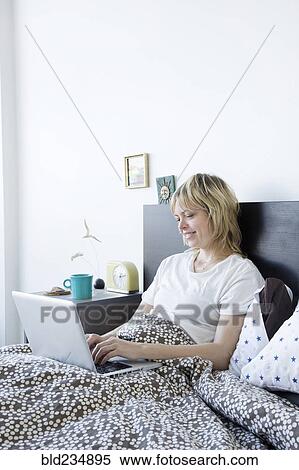 Stock Photography - Caucasian woman using laptop in bed. Fotosearch