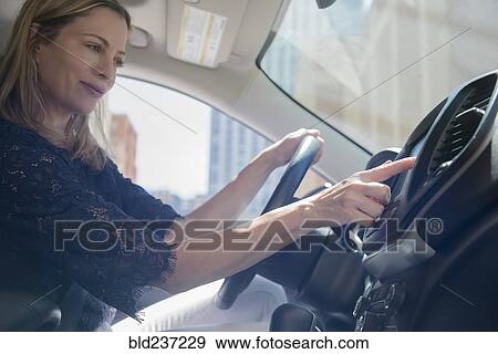 Stock Photo - Caucasian woman using touch screen on dashboard of car. Fotosearch