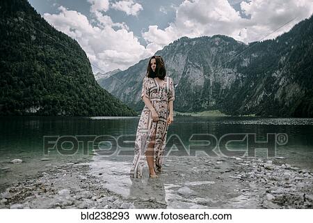 Stock Image - Caucasian woman wading in near mountain lake. Fotosearch
