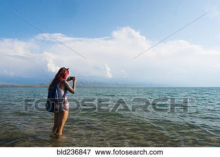 Caucasian woman wading in ocean photographing with cell phone View Large Photo Image Stock Photo - Caucasian woman wading in ocean photographing with cell phone. Fotosearch