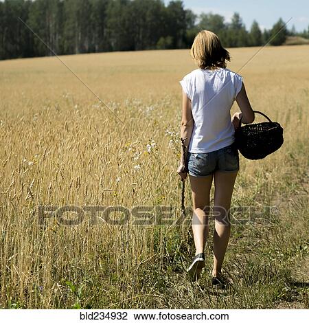 Caucasian woman walking in field carrying basket and stick View Large Photo Image Stock Image - Caucasian woman walking in field carrying basket and stick. Fotosearch