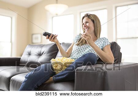 Stock Photography - Caucasian woman watching television and eating bowl of popcorn. Fotosearch