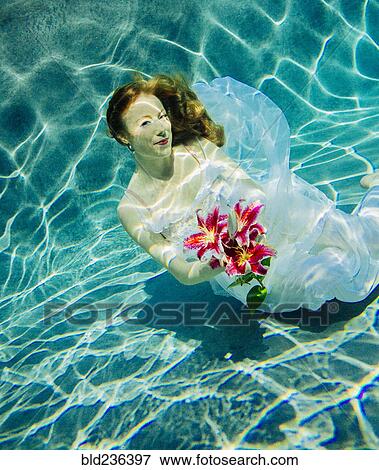 Caucasian woman wearing dress holding bouquet of flowers underwater View Large Photo Image Stock Photo - Caucasian woman wearing dress holding bouquet of flowers underwater. Fotosearch