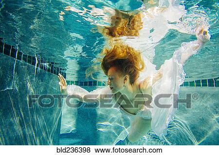 Caucasian woman wearing dress swimming underwater View Large Photo Image Stock Photo - Caucasian woman wearing dress swimming underwater. Fotosearch