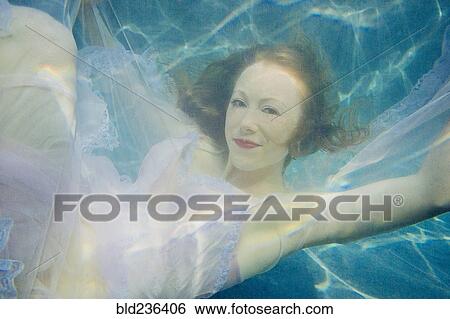 Caucasian woman wearing dress swimming underwater View Large Photo Image Stock Photograph - Caucasian woman wearing dress swimming underwater. Fotosearch