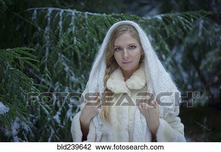 Stock Image - Caucasian woman wearing fur coat in snowy forest. Fotosearch