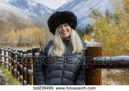 Caucasian woman wearing fur hat leaning on wooden fence in winter View Large Photo Image Stock Photo - Caucasian woman wearing fur hat leaning on wooden fence in winter. Fotosearch