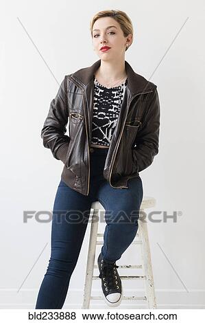 Caucasian woman wearing leather jacket sitting on stool View Large Photo Image Stock Photo - Caucasian woman wearing leather jacket sitting on stool. Fotosearch