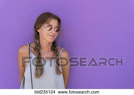 Caucasian woman wearing sunglasses leaning on purple wall View Large Photo Image Picture - Caucasian woman wearing sunglasses leaning on purple wall. Fotosearch