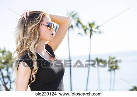 Picture - Caucasian woman with hand in hair near ocean. Fotosearch