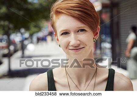 Stock Photo - Caucasian woman with nose ring smiling on city sidewalk. Fotosearch