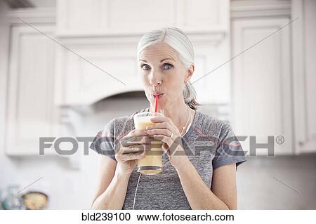 Stock Image - Caucasian women drinking smoothie with straw. Fotosearch