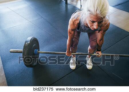Stock Photography - Caucasian women lifting barbell in gymnasium. Fotosearch