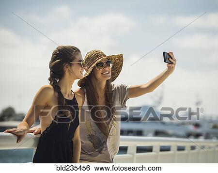 Stock Photograph - Caucasian women posing for cell phone selfie. Fotosearch