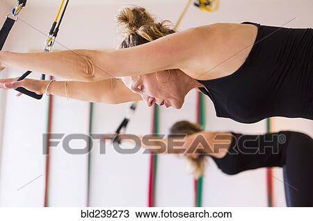 Stock Image - Caucasian women using resistance bands in gymnasium. Fotosearch