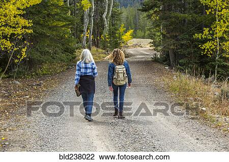 Stock Image - Caucasian women walking on forest path. Fotosearch