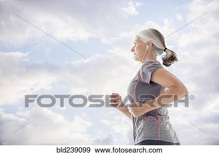 Caucasian women wearing earbuds running against clouds View Large Photo Image Stock Photo - Caucasian women wearing earbuds running against clouds. Fotosearch