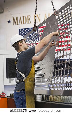 Stock Photography - Caucasian worker fabricating metal in factory. Fotosearch