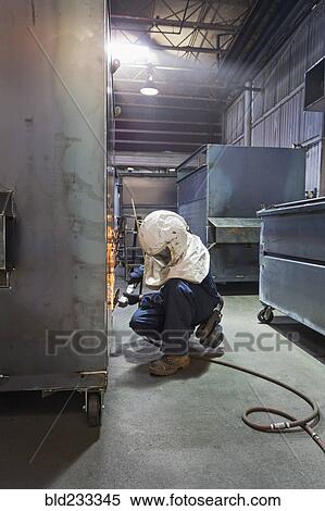 Caucasian worker grinding metal container in factory View Large Photo Image Stock Photography - Caucasian worker grinding metal container in factory. Fotosearch