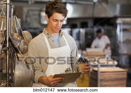 Caucasian worker looking at clipboard in bakery View Large Photo Image Stock Photo - Caucasian worker looking at clipboard in bakery. Fotosearch