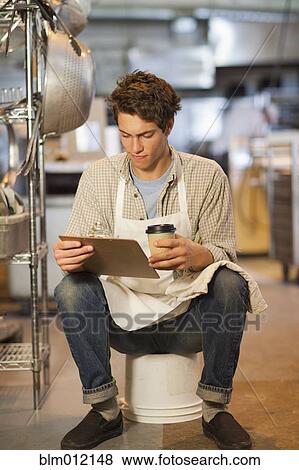 Stock Photo - Caucasian worker looking at clipboard in bakery. Fotosearch