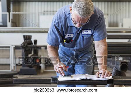 Caucasian worker using calculator in factory View Large Photo Image Stock Image - Caucasian worker using calculator in factory. Fotosearch