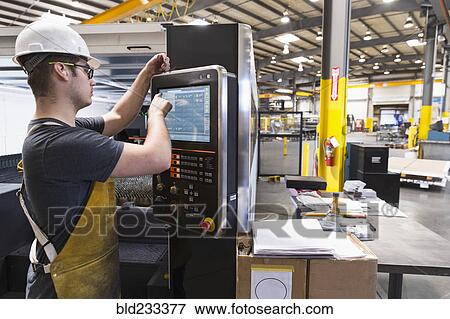 Stock Photo - Caucasian worker using control panel in factory. Fotosearch