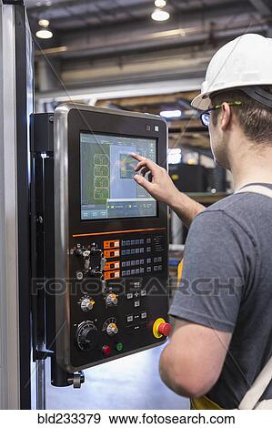 Stock Photo - Caucasian worker using control panel in factory. Fotosearch