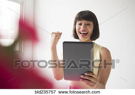 Celebrating Hispanic woman using digital tablet View Large Photo Image Stock Photo - Celebrating Hispanic woman using digital tablet. Fotosearch