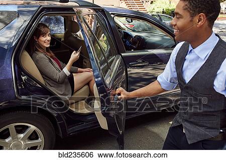 Stock Photograph - Chauffeur opening car door for businesswoman. Fotosearch