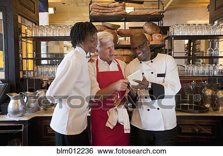 Stock Photograph - Chef and wait staff going over menu. Fotosearch