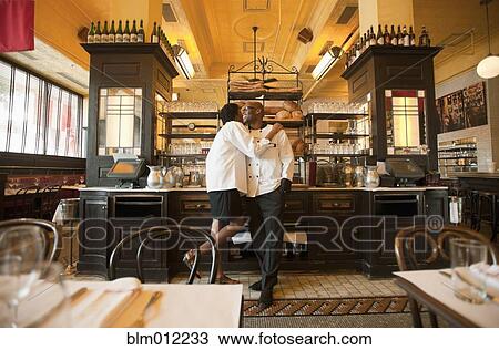 Stock Image - Chef and waitress hugging in restaurant. Fotosearch