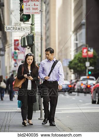 Chinese business people in city texting on cell phone View Large Photo Image Stock Photography - Chinese business people in city texting on cell phone. Fotosearch