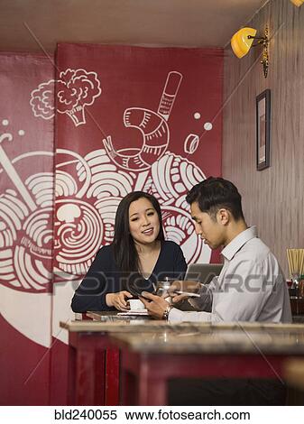 Chinese business people texting on cell phone in restaurant View Large Photo Image Stock Photography - Chinese business people texting on cell phone in restaurant. Fotosearch