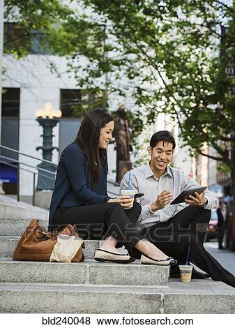 Chinese business people using technology on staircase at lunch View Large Photo Image Stock Photo - Chinese business people using technology on staircase at lunch. Fotosearch