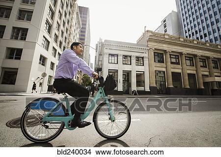 Picture - Chinese businessman commuting on bicycle in city. Fotosearch