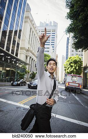 Chinese businessman hailing taxi in city View Large Photo Image Stock Image - Chinese businessman hailing taxi in city. Fotosearch