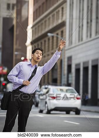 Chinese businessman hailing taxi in city View Large Photo Image Stock Photo - Chinese businessman hailing taxi in city. Fotosearch