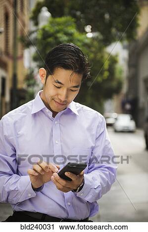Chinese businessman texting on cell phone in city View Large Photo Image Stock Image - Chinese businessman texting on cell phone in city. Fotosearch