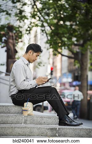 Chinese businessman texting on cell phone during lunch in city View Large Photo Image Stock Image - Chinese businessman texting on cell phone during lunch in city. Fotosearch