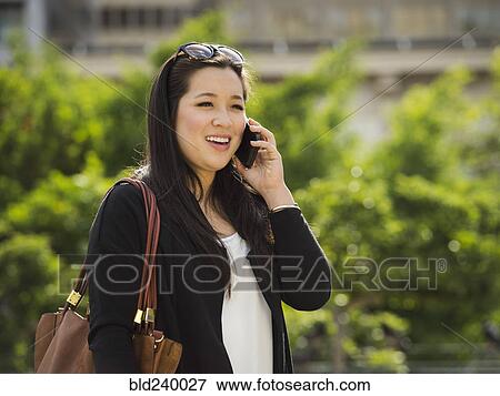 Chinese businesswoman talking on cell phone outdoors View Large Photo Image Stock Photo - Chinese businesswoman talking on cell phone outdoors. Fotosearch