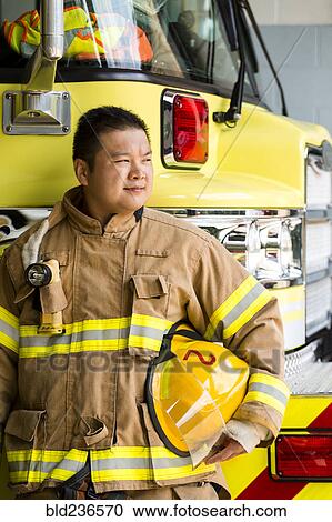 Stock Image - Chinese fireman standing near fire trucks. Fotosearch