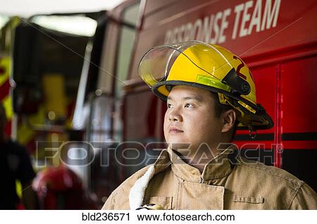 Stock Image - Chinese fireman standing near fire truck. Fotosearch