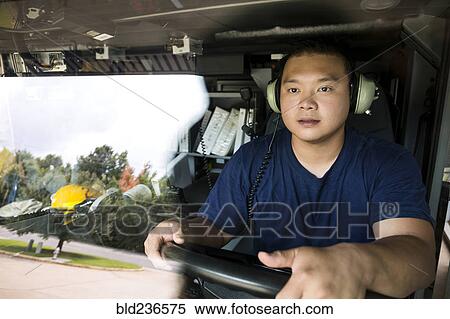 Stock Photography - Chinese fireman wearing headphones driving fire truck. Fotosearch