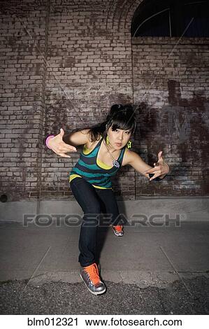 Stock Image - Chinese woman breakdancing in urban area. Fotosearch