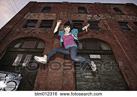 Stock Photograph - Chinese woman breakdancing in urban area. Fotosearch