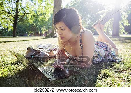 Chinese woman laying on grass using laptop View Large Photo Image Stock Image - Chinese woman laying on grass using laptop. Fotosearch